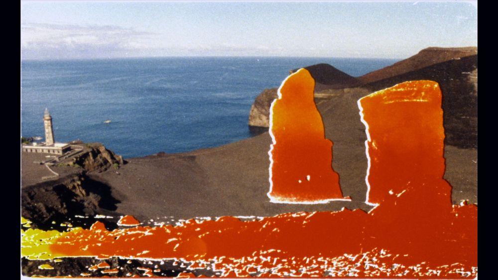 A landscape of a large body of water and surrounding terrain, a small building seen in the distance. There are red abstract shapes superimposed on top of the image toward the bottom. 