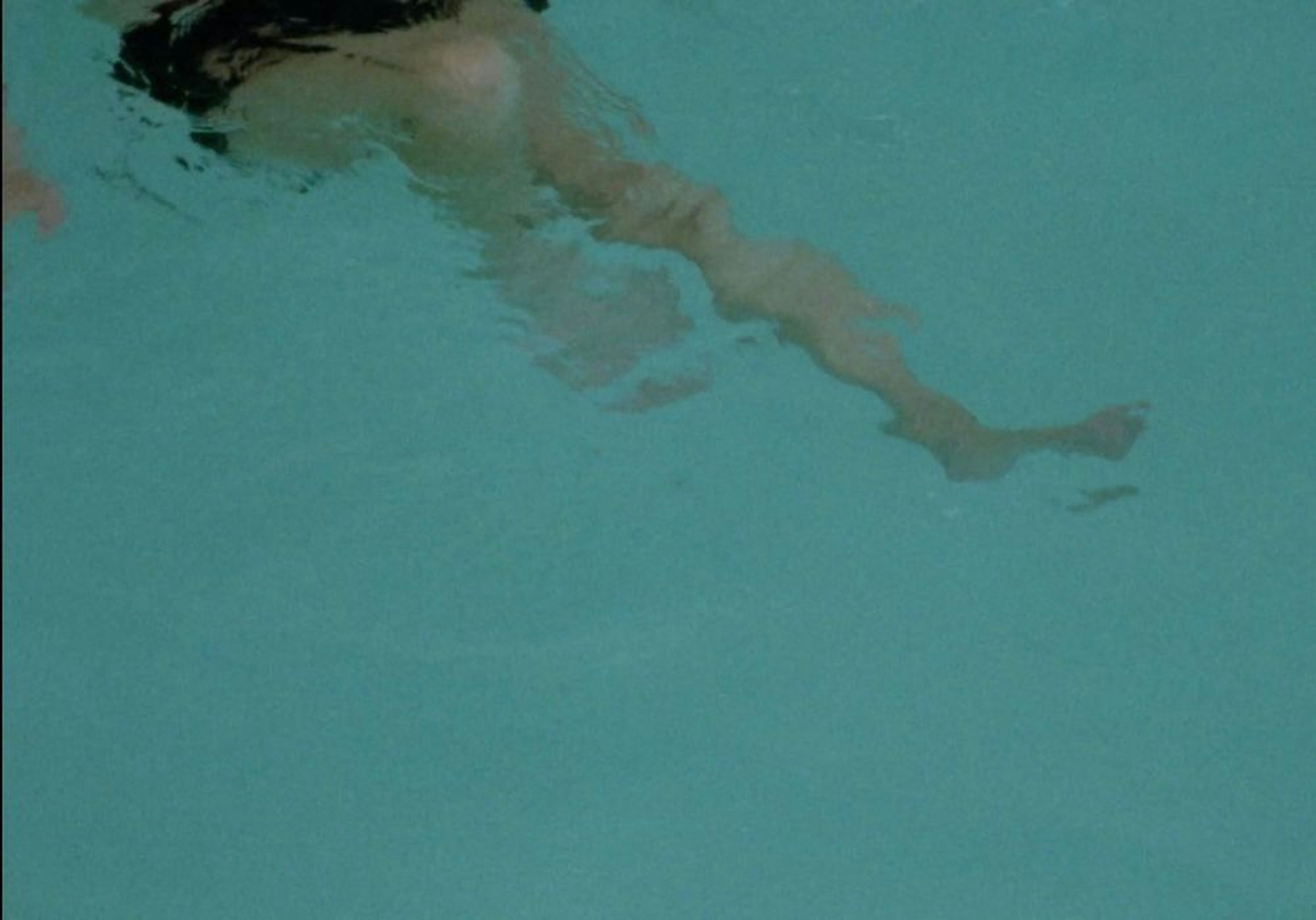 A person swimming, focusing on her legs and arms which are fragmented from the water.